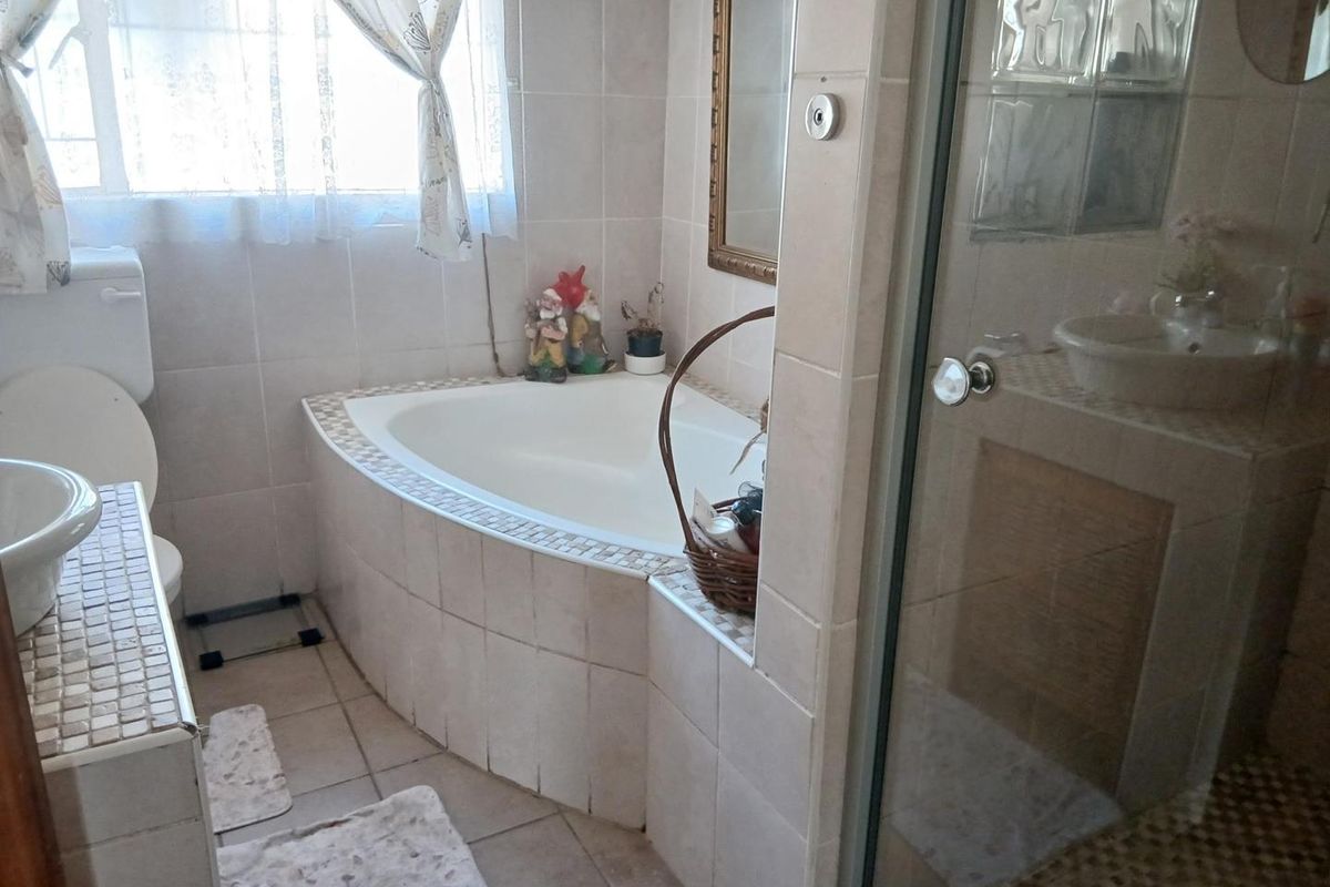 A functional bathroom featuring a corner bathtub, a separate glass-enclosed shower, and tiled surfaces throughout.