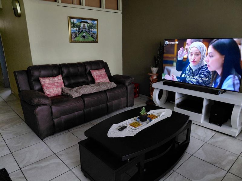 A comfortable living room featuring neutral wall tones and ceramic floor tiles, providing a functional space for relaxation and entertainment.