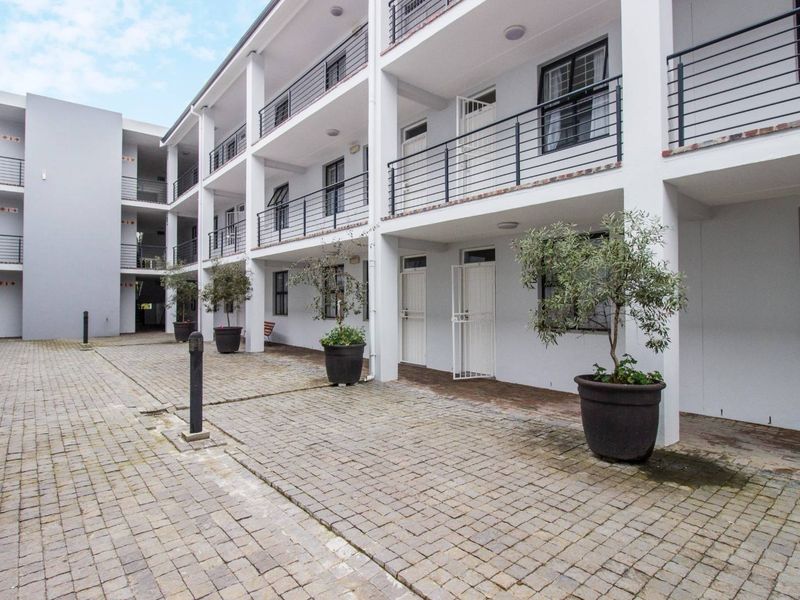 A well-maintained multi-story apartment complex featuring a paved courtyard, secure balcony railings, and functional exterior lighting.