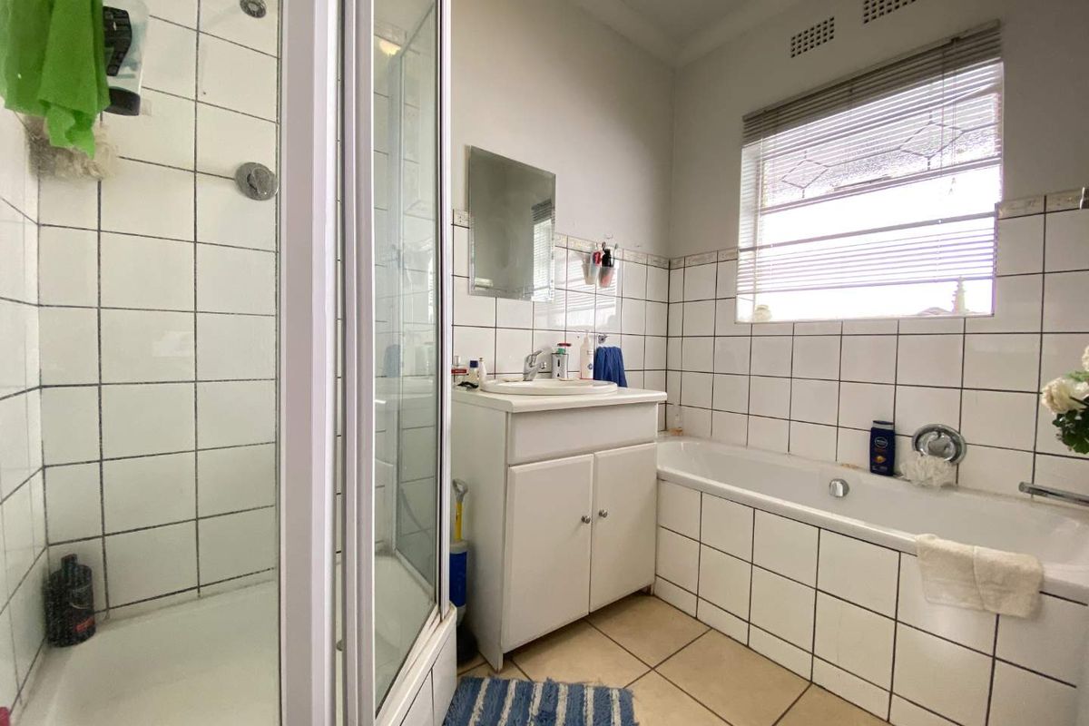 A functional bathroom featuring a separate shower enclosure, a built-in bathtub, and a vanity basin with tiled walls and flooring.