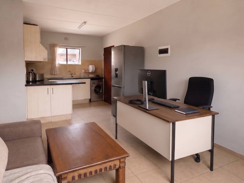 Open-plan living area featuring a functional kitchen with built-in cabinetry, tiled flooring, and a combined workspace layout.
