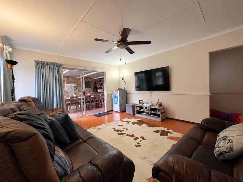Spacious living room featuring tiled flooring, a ceiling fan, and large sliding glass doors providing access to the outdoor patio area.