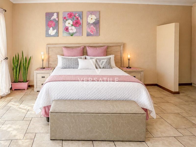 Spacious bedroom featuring neutral tiled flooring, built-in cupboards, and a sliding glass door providing natural light.