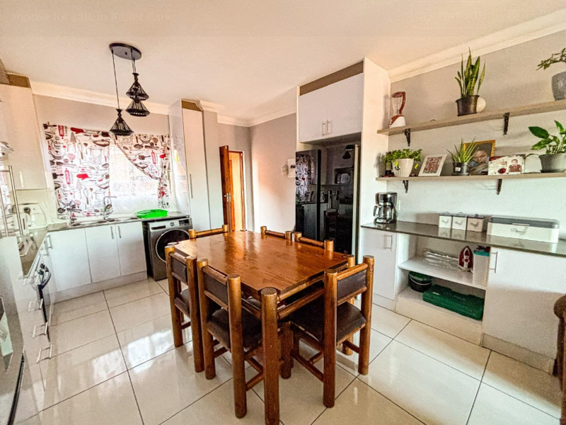 Open-plan kitchen and dining area featuring tiled floors, built-in cabinetry, open shelving, and integrated oven, providing a functional space for cooking and dining.