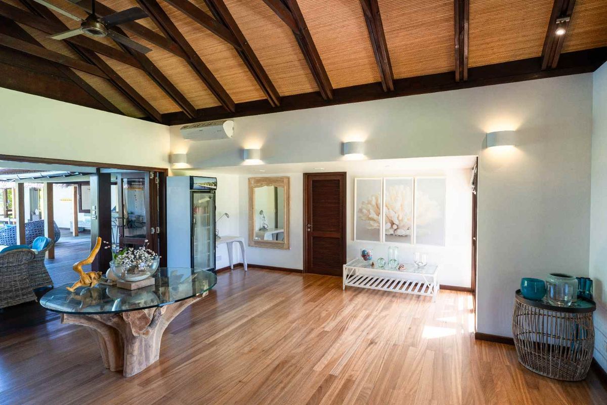 Spacious living area featuring high vaulted timber-beamed ceilings with woven inlay, polished hardwood flooring, and direct access to an outdoor patio.