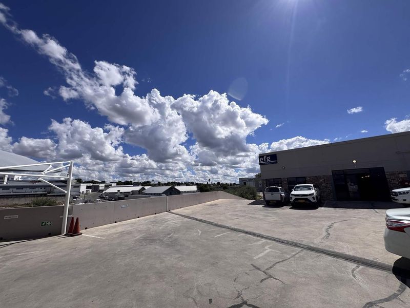 Exterior view of a commercial property featuring a paved parking area and building entrance with clear sky.