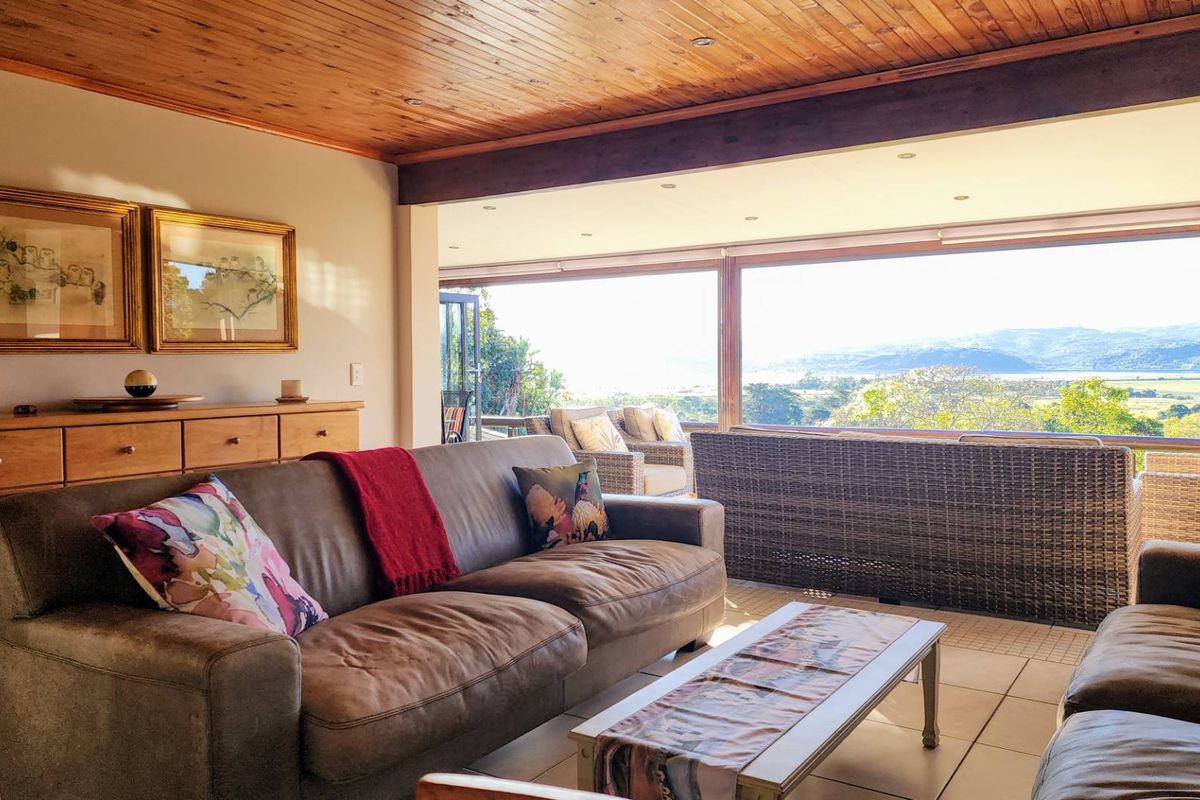 Spacious living area featuring a warm timber-clad ceiling, large sliding glass doors, and expansive views of the surrounding landscape.