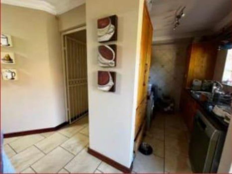 A functional scullery area featuring tiled flooring, built-in cabinetry, and a security gate, providing additional prep and storage space adjacent to the main kitchen.