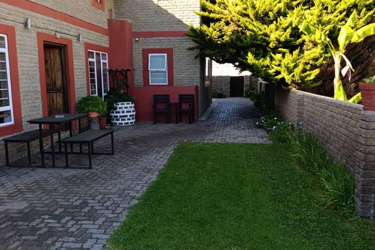 A well-maintained rear courtyard featuring brick paving, a small lawn area, and a brick boundary wall, providing a private outdoor space.