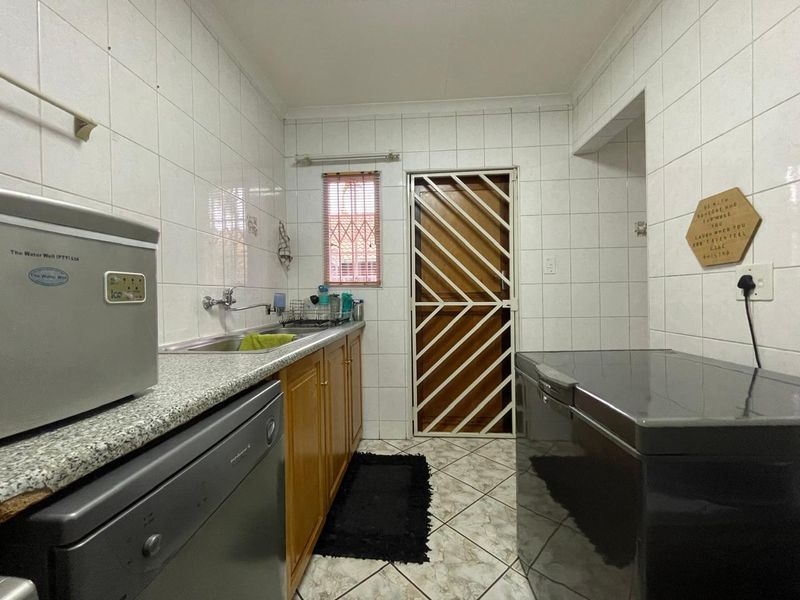 Functional laundry room featuring tiled walls, built-in cabinetry, a stainless steel sink, and a secure exterior door.