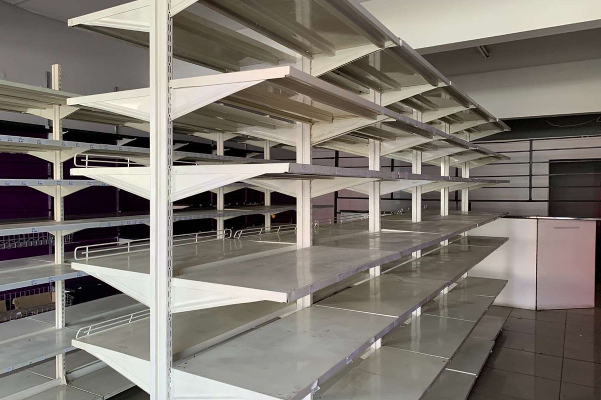 Empty retail space featuring modular metal shelving units, slatwall display panels, and tiled flooring, suitable for various commercial or retail business applications.