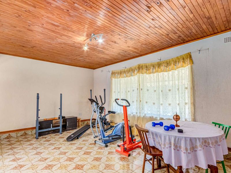 A living area featuring a distinctive timber tongue and groove ceiling and patterned tiled flooring, offering a versatile space for various uses.