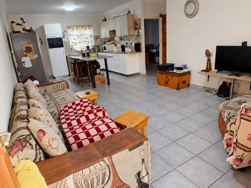 Spacious open-plan living area featuring tiled flooring and a functional kitchen with built-in cabinetry and a central island.