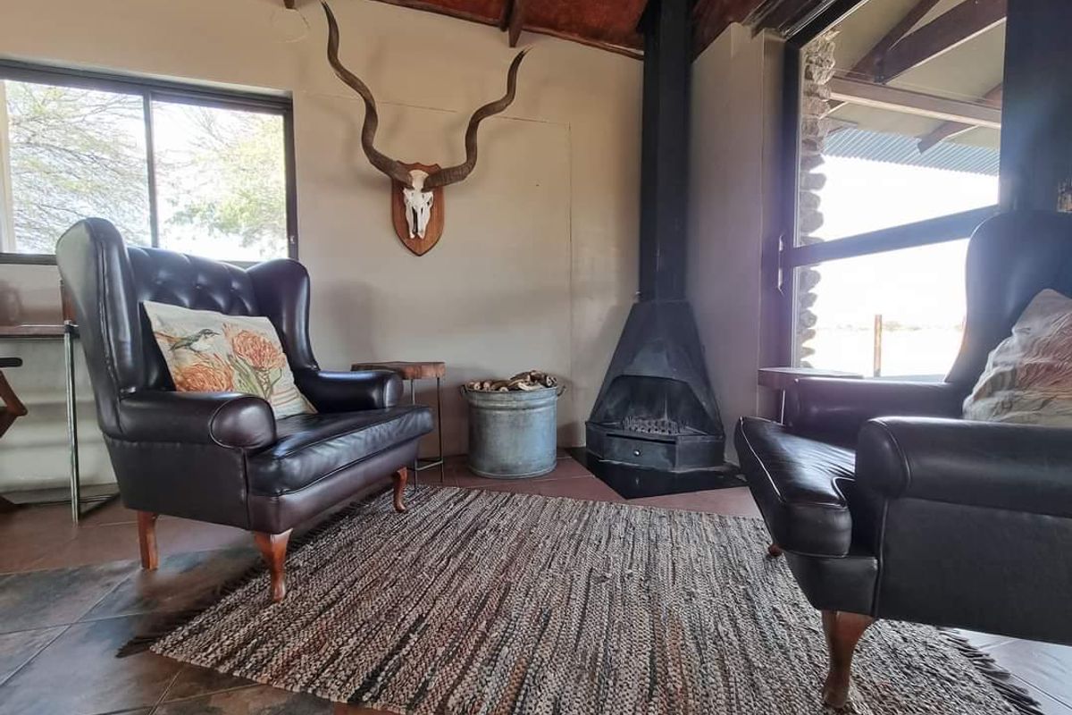 Cozy living area featuring a built-in corner fireplace, exposed timber roof beams, and large windows providing natural light and views.