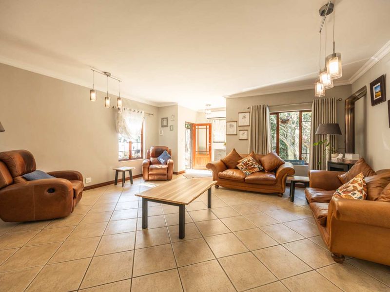 Spacious living room featuring neutral walls, tiled flooring, and a wood-burning fireplace, offering a comfortable and inviting atmosphere with natural light.