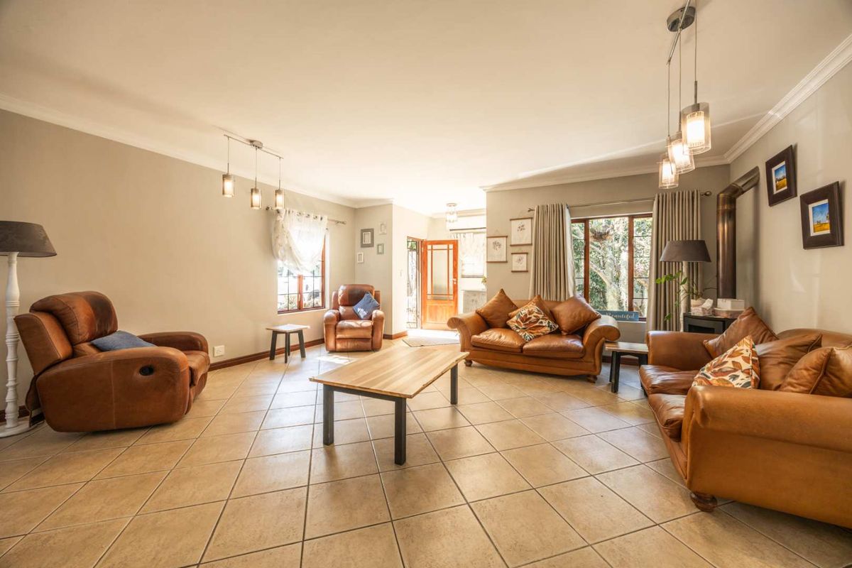 Spacious living room featuring neutral walls, tiled flooring, and a wood-burning fireplace, offering a comfortable and inviting atmosphere with natural light.