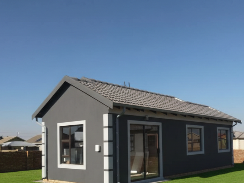 A modern, well-maintained detached house featuring a dark grey exterior, tiled roof, and aluminium-framed windows set within a neat garden.