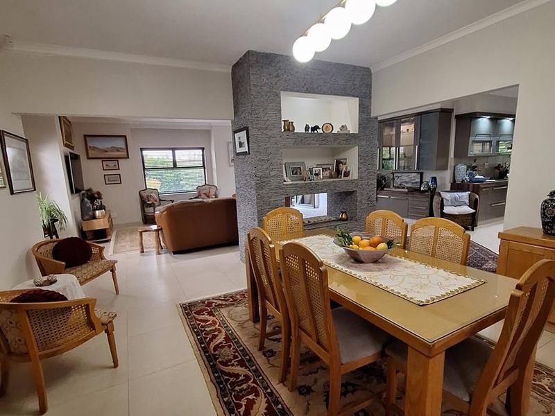 Spacious open-plan dining and living area featuring a central stone-clad feature wall with recessed shelving and modern pendant lighting.