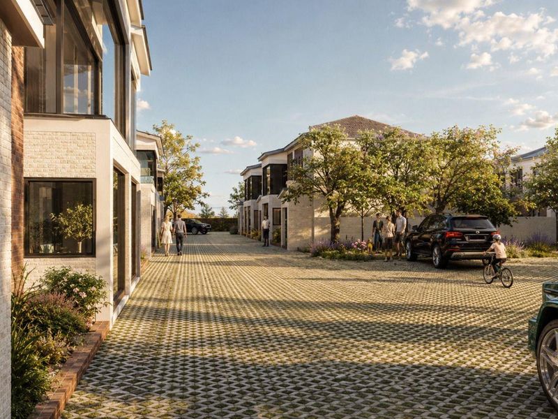 A modern townhouse complex featuring a paved driveway, brick facade architecture, and landscaped surroundings in a residential setting.