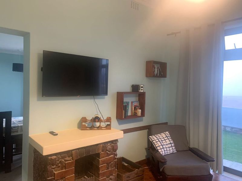 Living room featuring a brick fireplace, light-colored walls, and a sliding glass door providing access to the outdoor area.