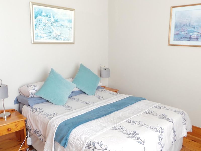 A cozy bedroom featuring warm timber flooring and neutral wall finishes, providing a comfortable and inviting sleeping space.