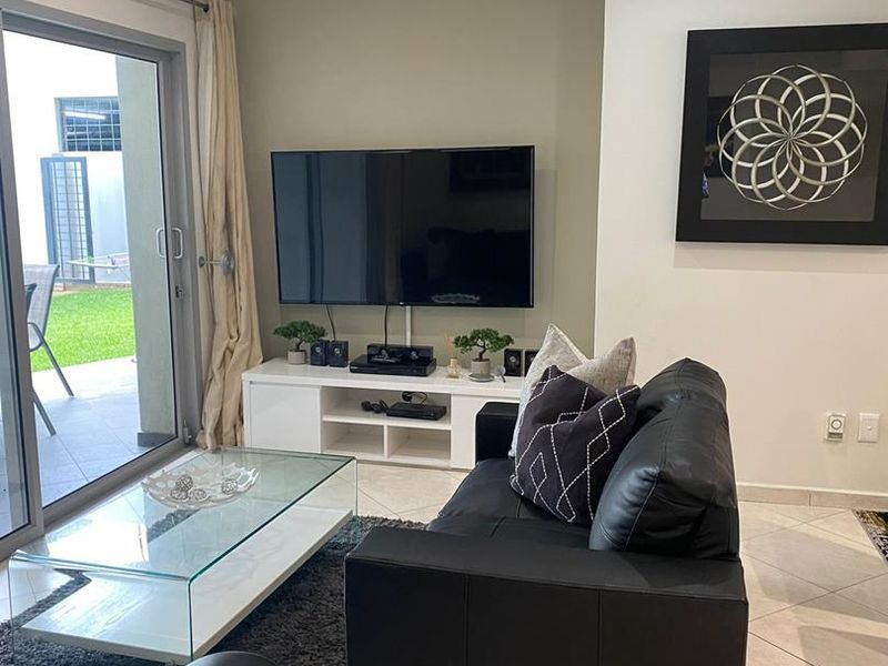 A well-maintained living room featuring tiled flooring, recessed downlights, and a large sliding glass door providing access to the outdoor patio area.
