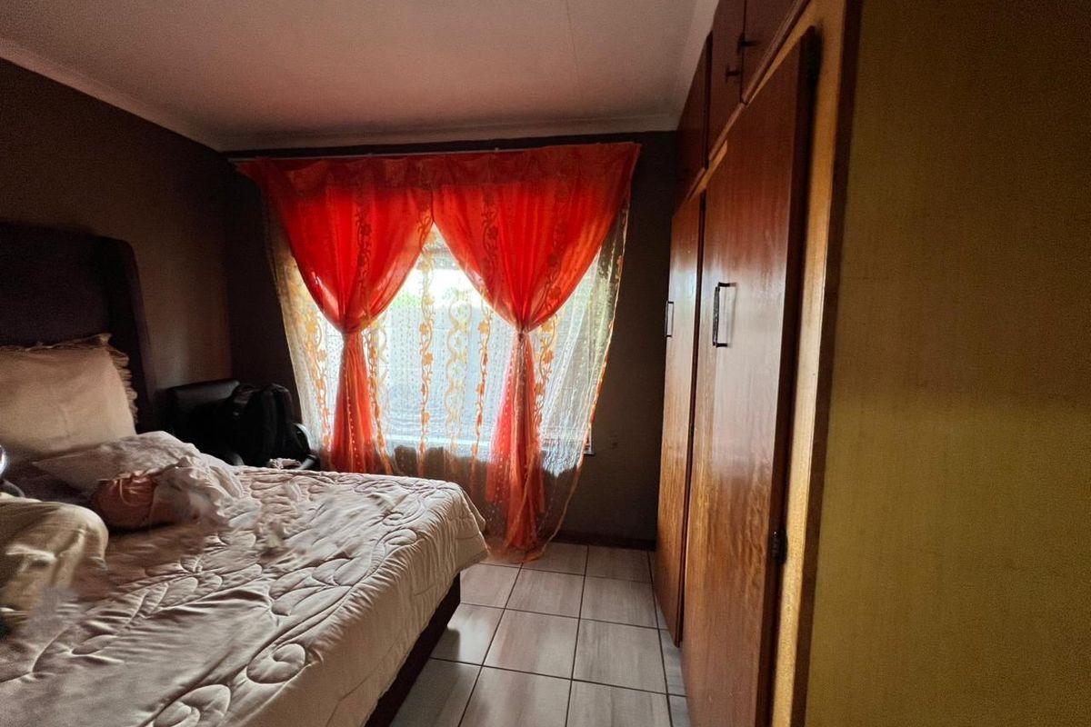 A bedroom featuring tiled flooring and built-in wooden cupboards, providing functional storage space.