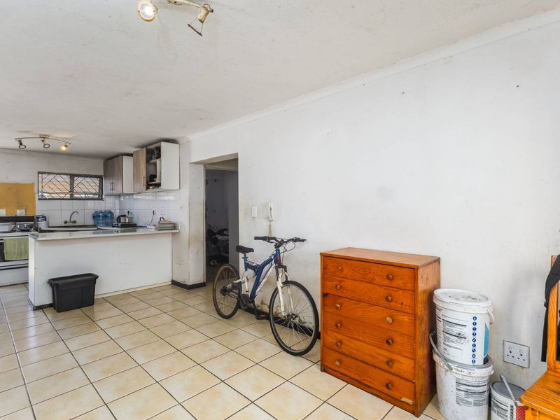Open plan living and kitchen area featuring tiled flooring, functional cabinetry, and a freestanding stove, requiring cosmetic updates to improve overall presentation.