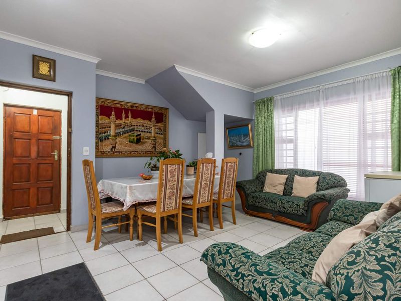 Open-plan living and dining area featuring tiled flooring, coved cornicing, and natural light through a large window.