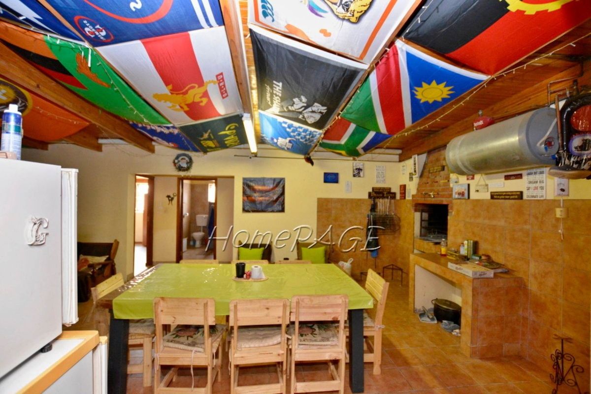 An informal entertainment area featuring a built-in brick braai, tiled flooring, and exposed timber ceiling beams.