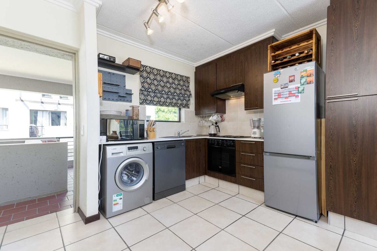 A functional kitchen featuring dark wood cabinetry, tiled flooring, a built-in oven with extractor fan, and a tiled backsplash.