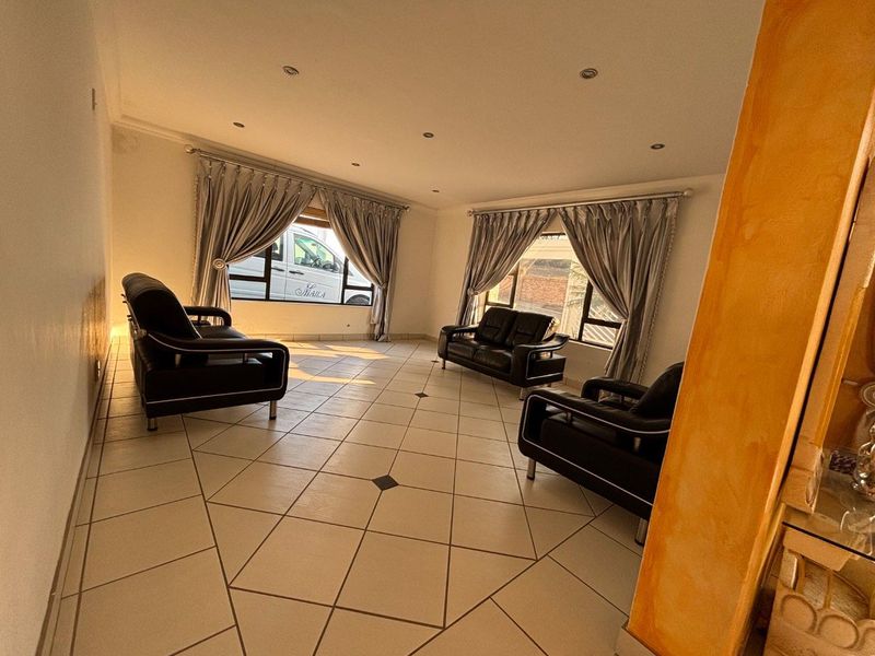 Spacious living room featuring large windows with curtain rods and tiled flooring with decorative inserts.
