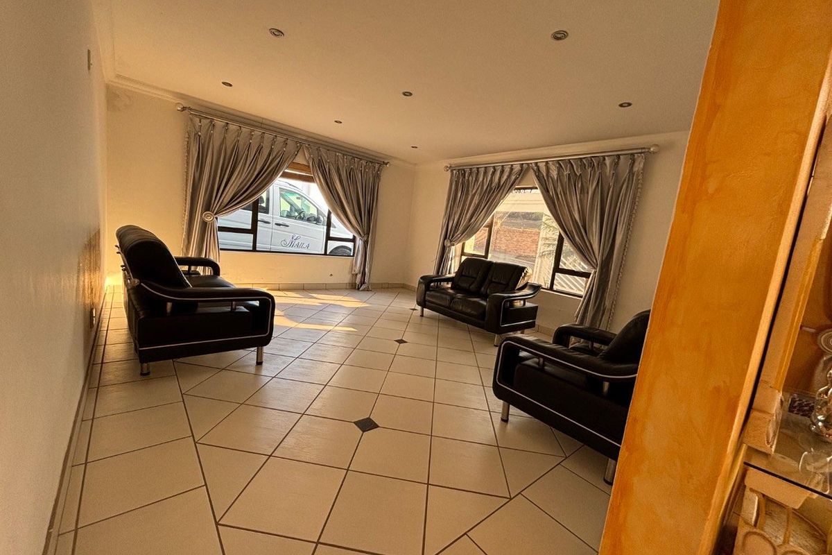 Spacious living room featuring large windows with curtain rods and tiled flooring with decorative inserts.