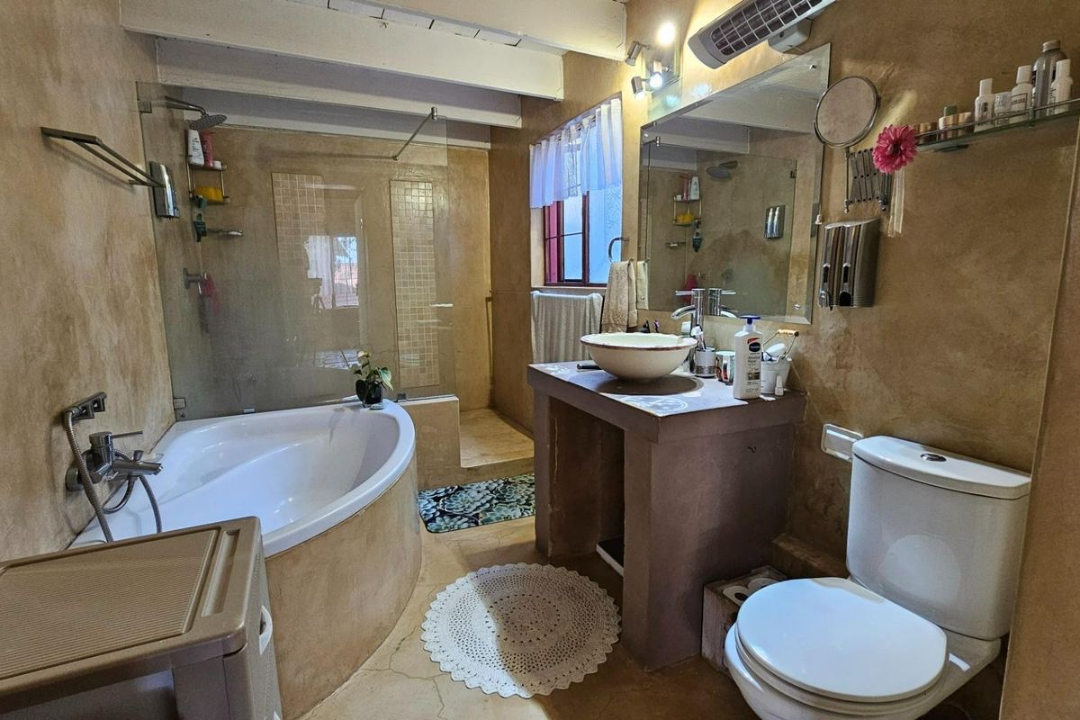 A rustic-style bathroom featuring a corner soaking tub, a glass-enclosed shower, a custom concrete vanity with a vessel sink, and a standard toilet.