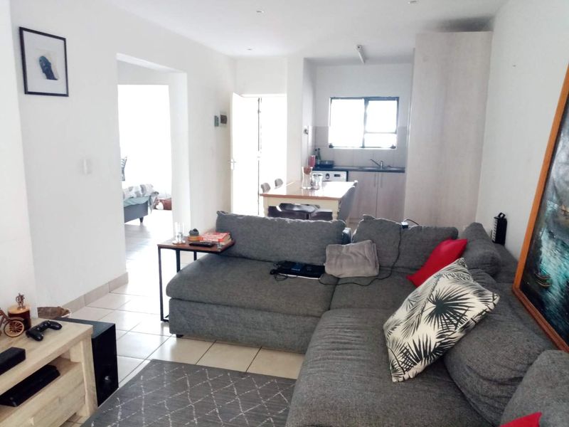 Open plan living area featuring tiled flooring and a functional kitchen space with built-in cabinetry and sink.