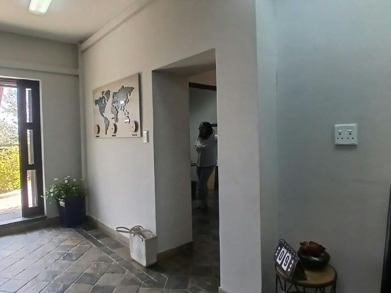 An office entrance area featuring tiled flooring, neutral walls, and direct access to an outdoor space through a glass-paneled door.