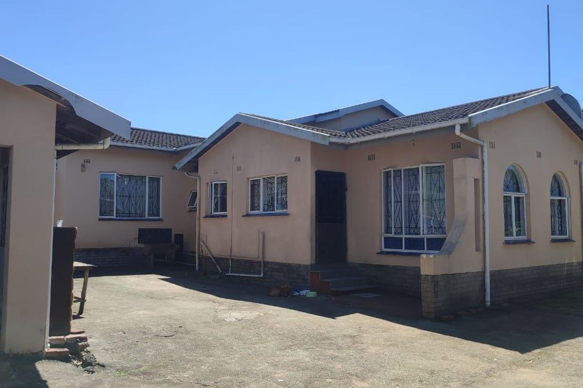 Exterior view of the house featuring a concrete driveway, tiled roof, and security bars on windows.