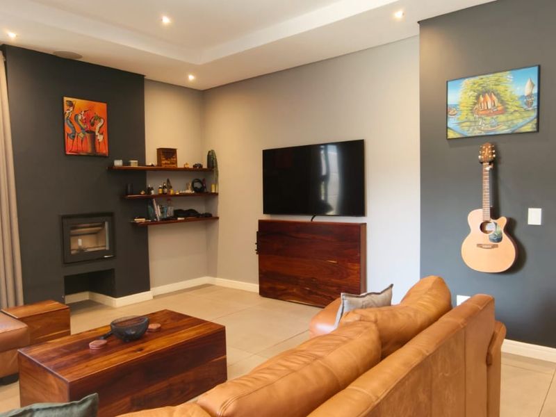Modern living room featuring a built-in fireplace, floating shelving, recessed ceiling lights, and large glass sliding doors leading to the exterior.
