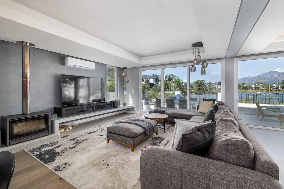 Modern living room featuring a sleek fireplace, split-system air conditioning, and large sliding glass doors opening to a scenic outdoor patio area.