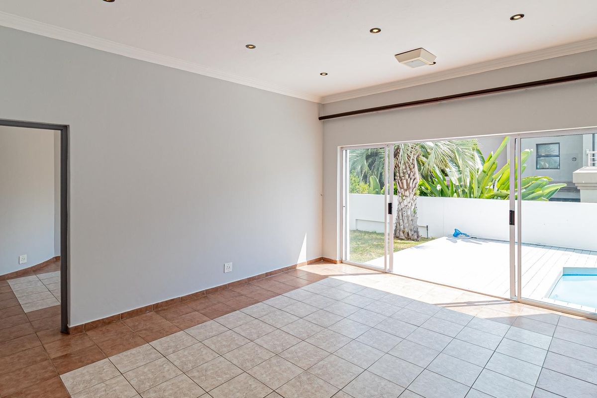 Spacious, light-filled living area featuring neutral walls, tiled flooring, and large sliding glass doors providing direct access to the patio and pool area.