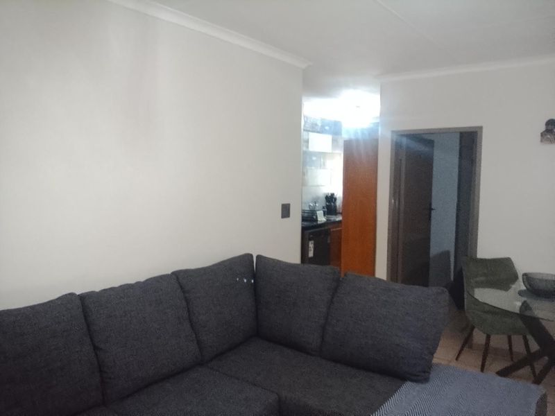 Open plan living area featuring neutral walls, coving, and a view through to the kitchen and adjacent room.
