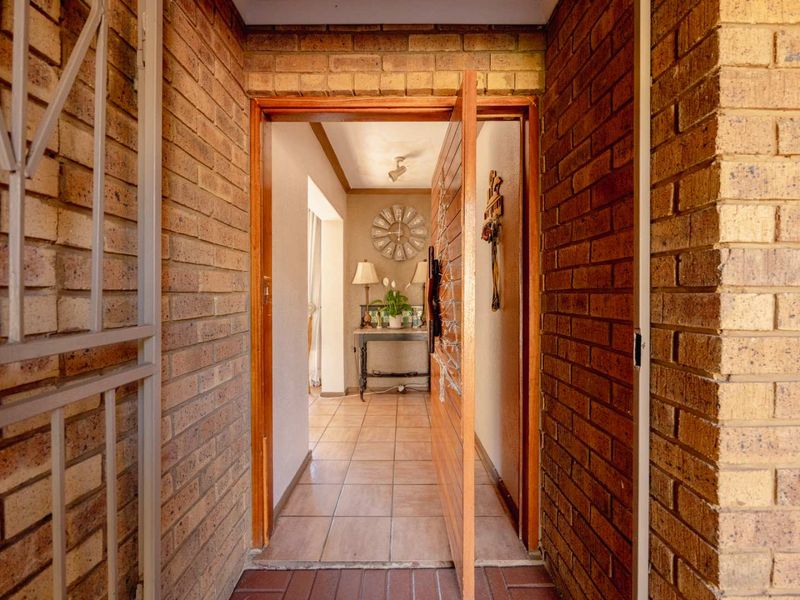 Entrance foyer featuring exposed brick walls, tiled flooring, and a timber door leading into the home interior.