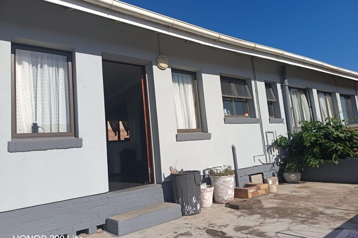 Rear exterior view of the townhouse featuring a concrete patio area, aluminium window frames, and painted brick facade.