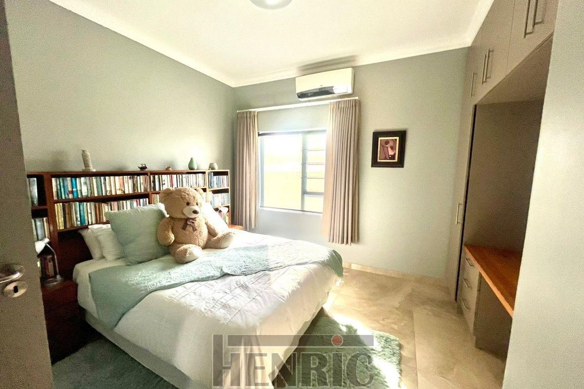 A well-maintained bedroom featuring built-in cabinetry, a desk area, and a wall-mounted air conditioning unit.