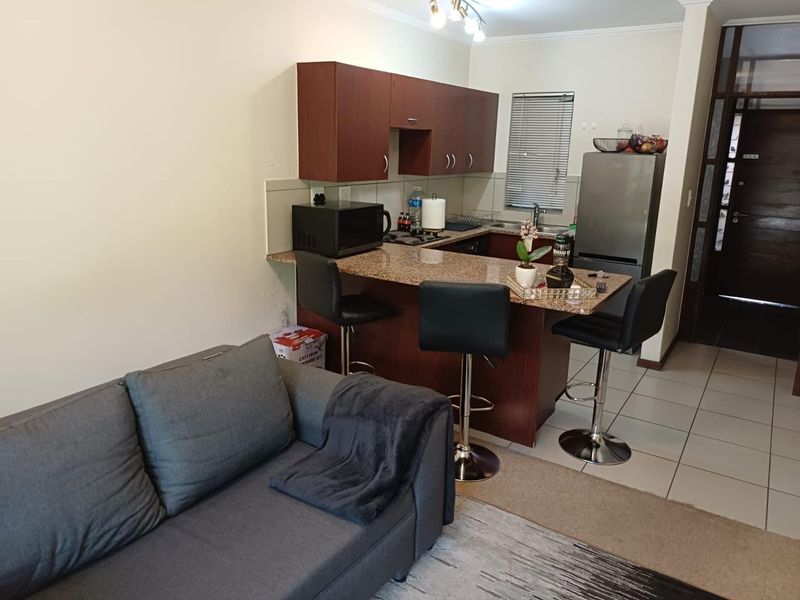 Open plan living area featuring a compact kitchen with granite countertops, built-in cabinetry, and a breakfast bar, seamlessly connected to the living space.