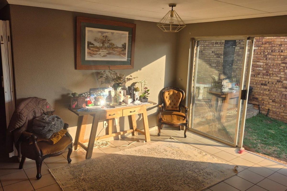 A living room featuring tiled flooring and a large sliding glass door providing access to the rear garden area.