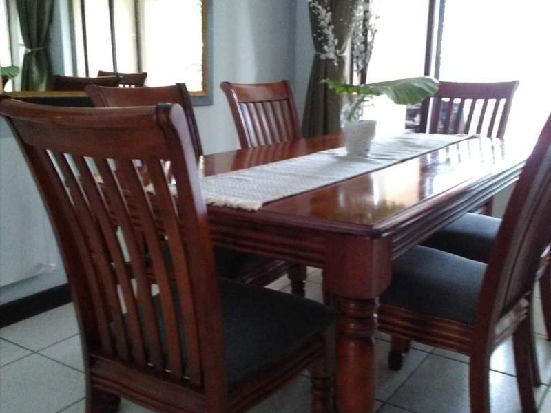 Dining area featuring tiled flooring, a large wall-mounted mirror, and access to an outdoor space through sliding glass doors.