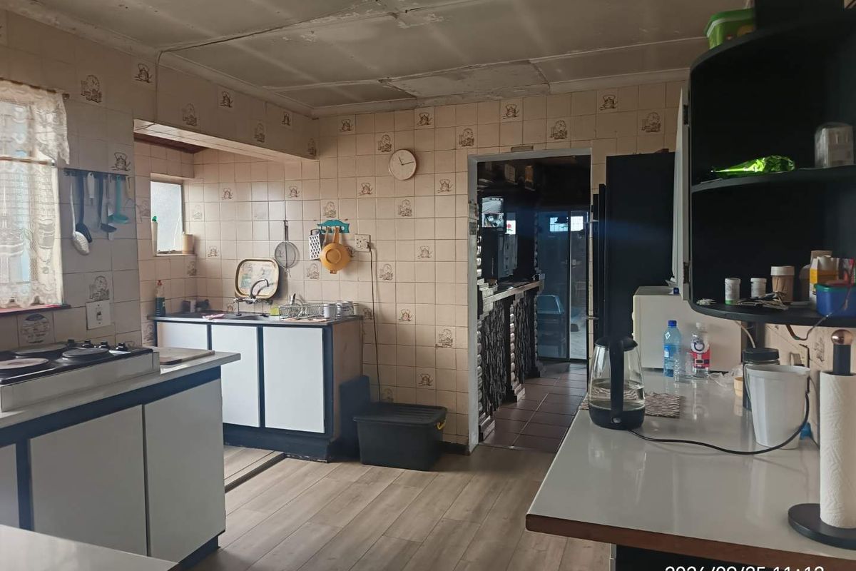 A dated kitchen featuring built-in cabinetry, laminate countertops, and tiled wall finishes, offering significant potential for a modern renovation.