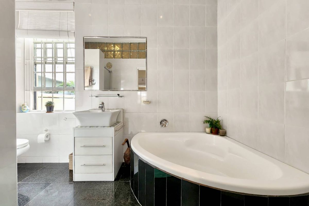 A functional bathroom featuring a corner bathtub, a modern vessel sink with vanity storage, and tiled finishes throughout.