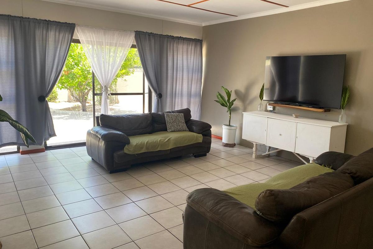 Spacious living room featuring neutral tiled flooring and a large sliding glass door providing direct access to the outdoor area.